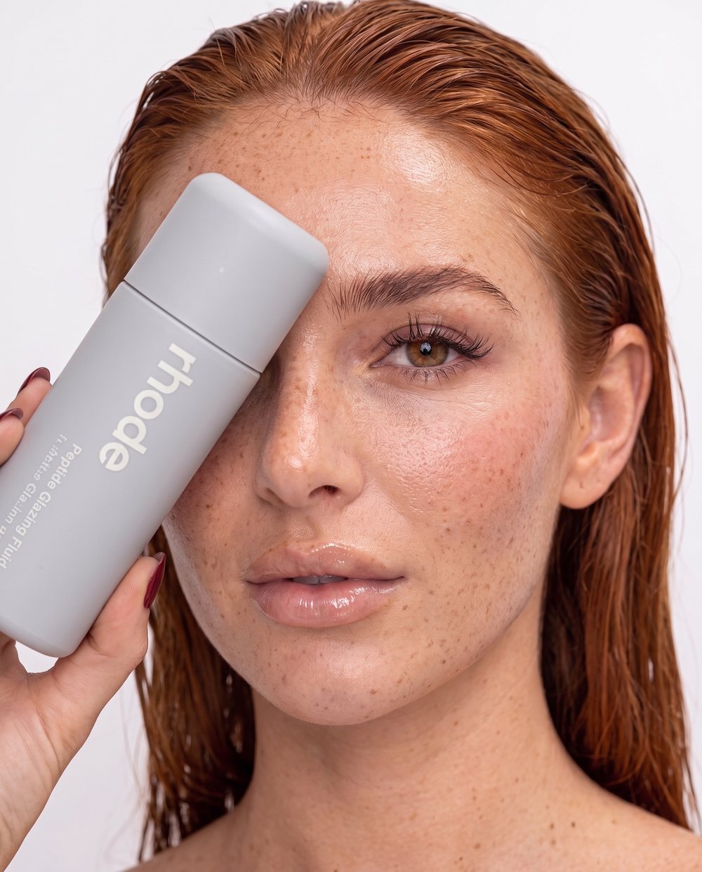 Elara houdt een skincareproduct voor haar oog